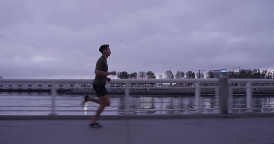 A man is running on a pathway beside a large body of water