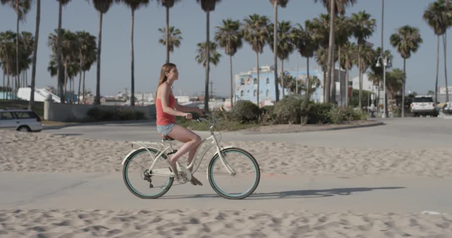 Woman rides a bike down the sidewalk near the beach