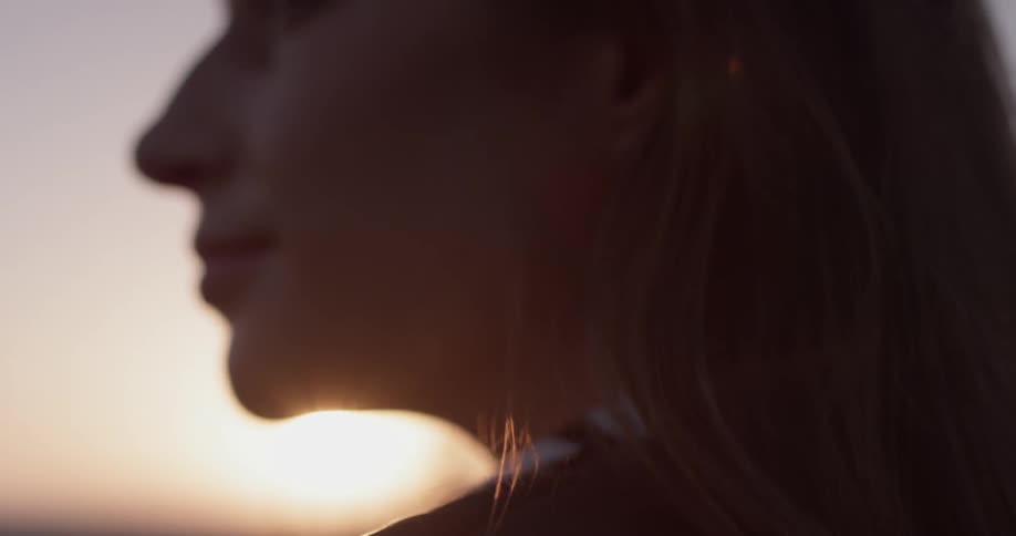 A woman sits in front of a brilliant sunset