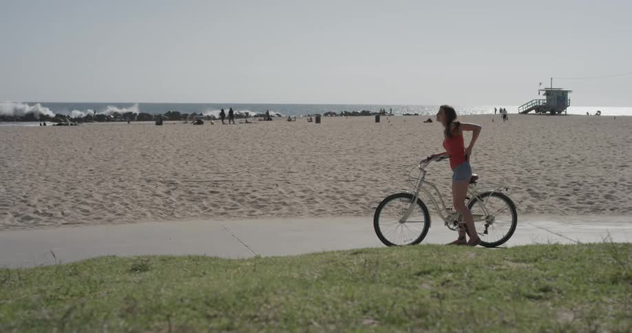 A woman rests her foot on a bike pedal as she looks at her phone