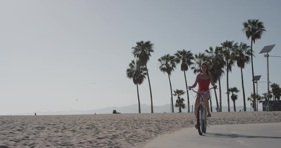 Woman rides her bike on the beach on a sunny day