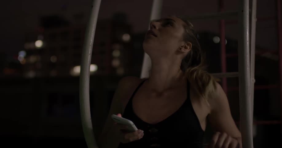 Woman scrolls on a phone while sitting outside at night