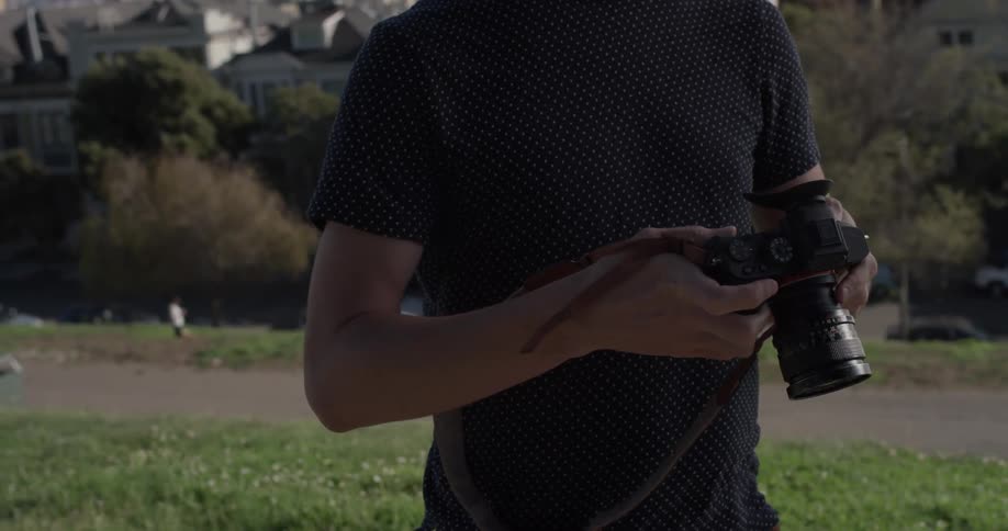 Man looks at his camera while standing in a park