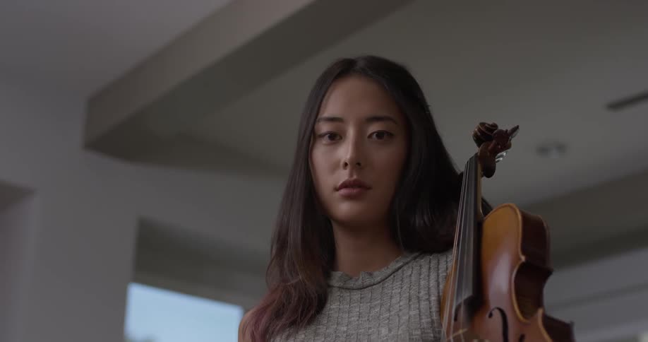 Woman holds a violin and stares downwards
