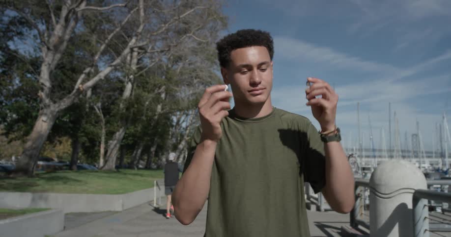 A man is walking outside and takes out headphones