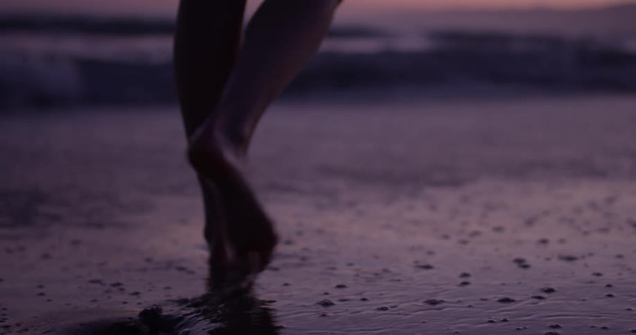 Closeup of women's feet walking in the surf in the evening sun