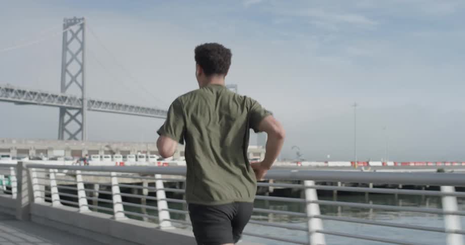 Man jogs on a bridge near the water