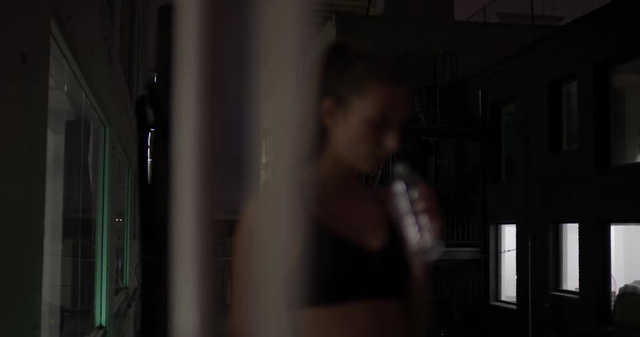 A woman drinks water in a dark building