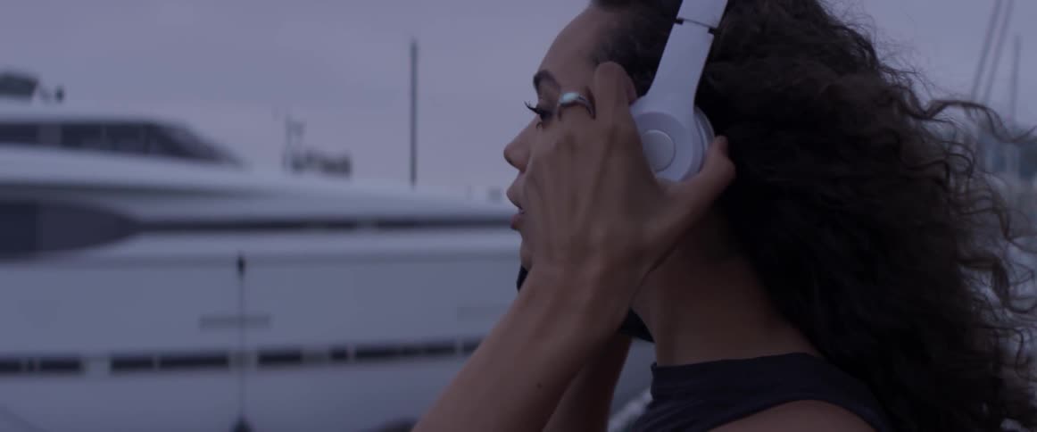 A woman grabbing headphones and putting them on her ears