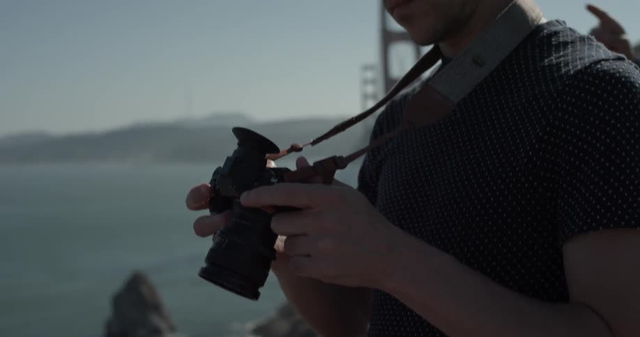 A man manipulates a telescopic camera then looks through the viewfinder