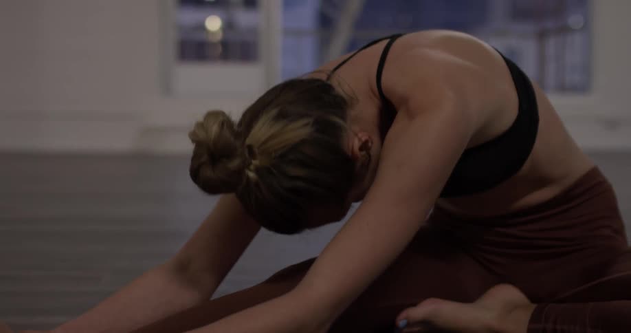 A woman bends one leg and leans forward to stretch