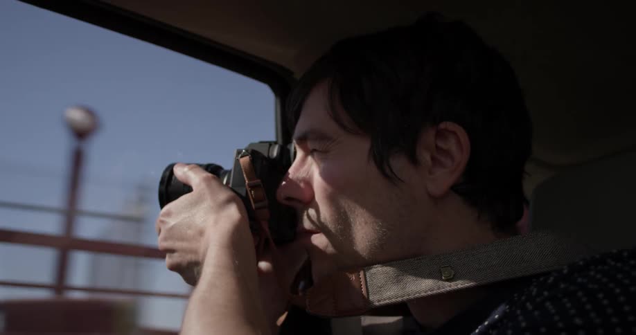 Man using a camera to take a photo out of a car