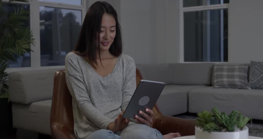 Woman laughing and smiling while talking into a tablet