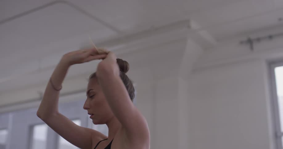 Woman putting her hair into a bun on top of her head