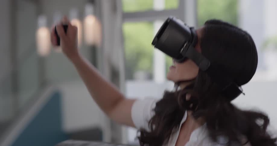 A woman is having playing a game in a virtual reality simulation with vr goggles