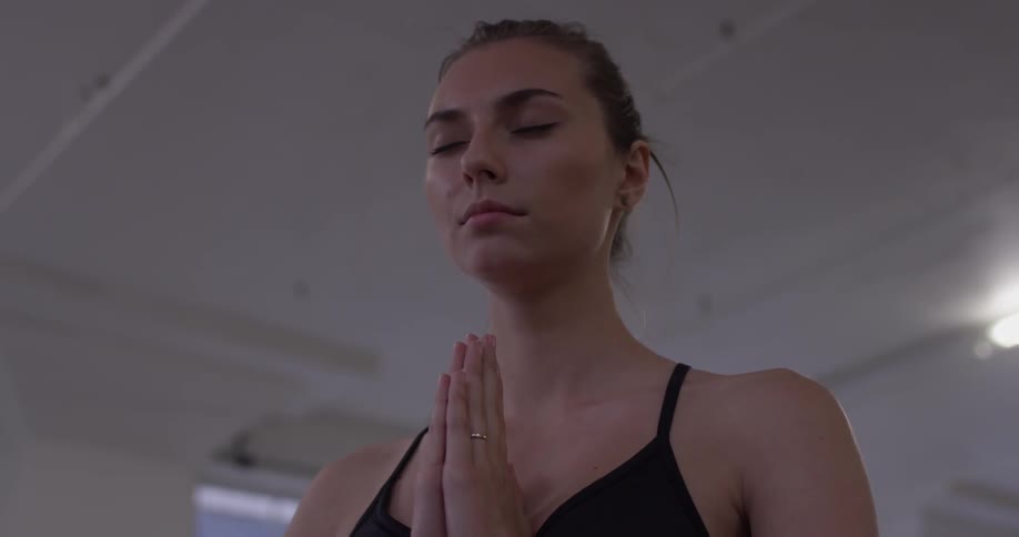 A woman closes her eyes and puts her hands together as if she was praying