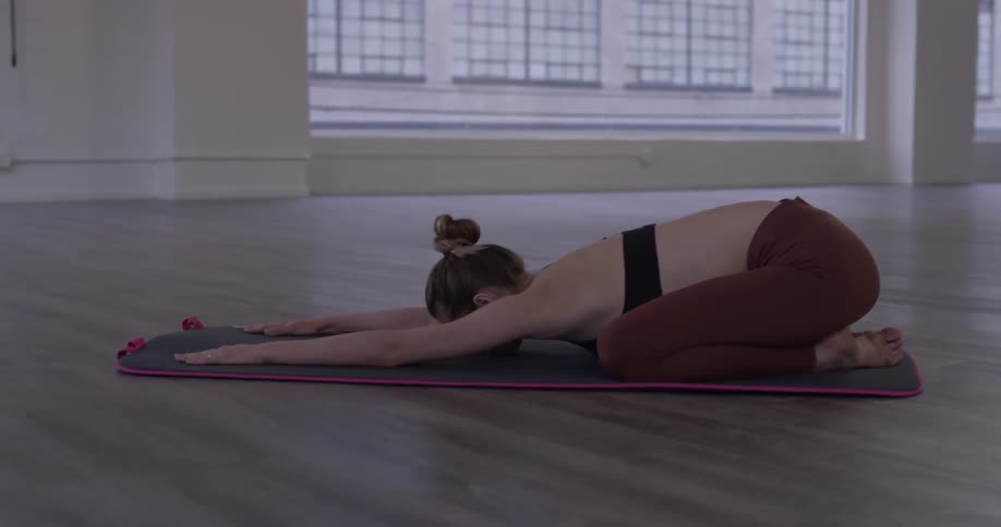 A woman bends forward from a kneeling position with her arms straight
