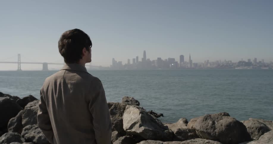 Man looks out at ocean near rocks