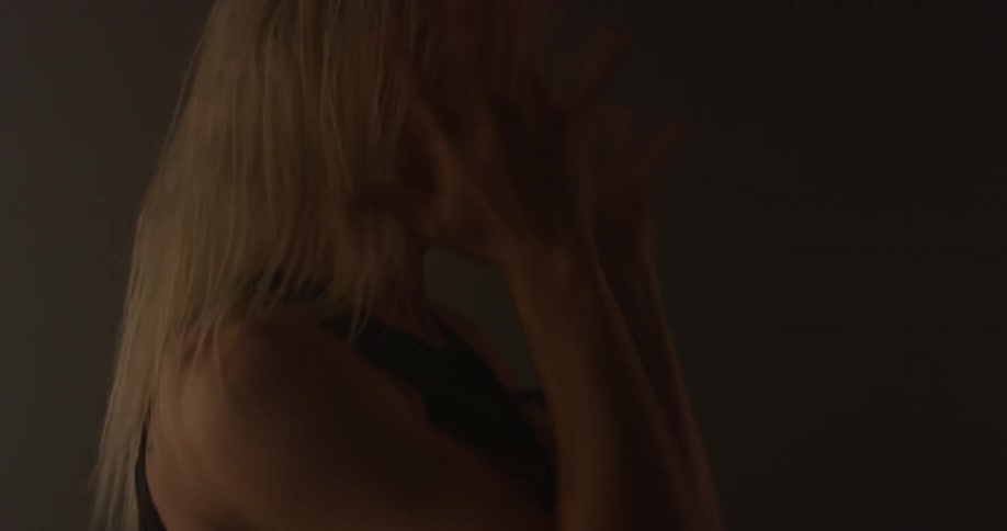 A woman is moving her hands as she dances inside in daylight