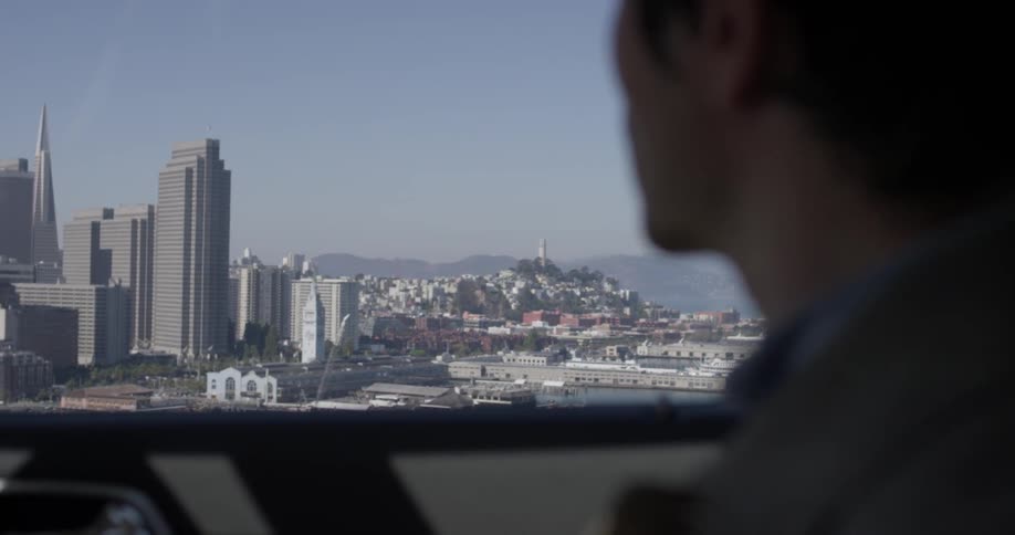 Man rides a bus looking out at a large city