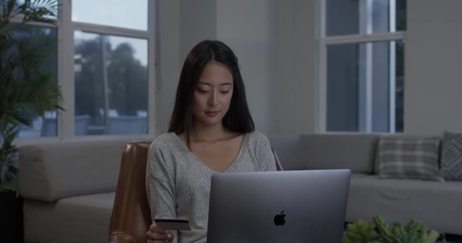 A woman grabbing a card behind a laptop