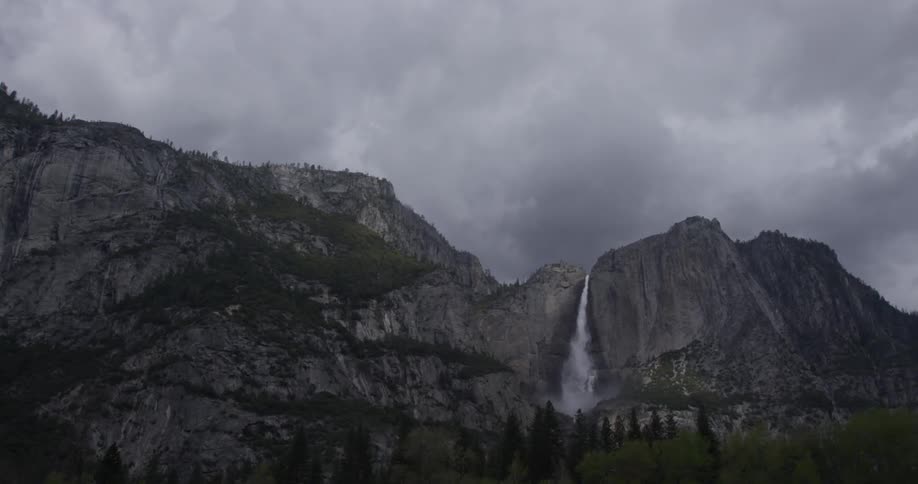 Yosemite falls are cascading down a cliff on a stormy day