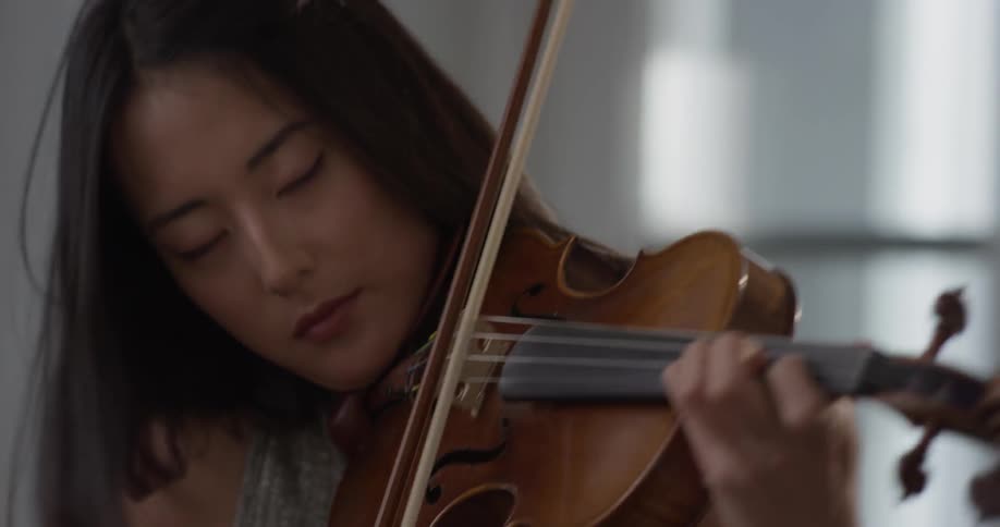 Woman plays the violin with her eyes closed