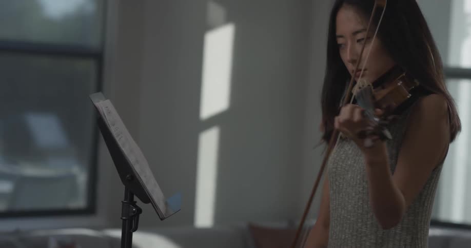 Woman puts sheet music on a stand playing a violin