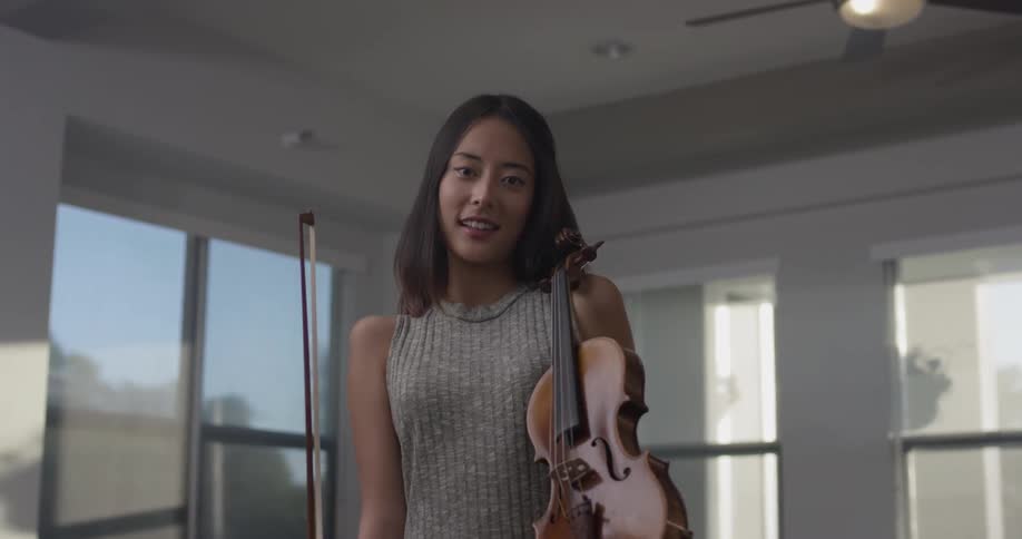 A woman smiling holding a violin
