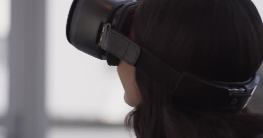 A woman puts on vr goggles and appears to be enjoying the experience as she looks around