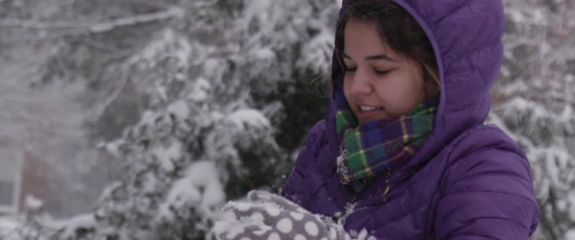 Happy young girl shaping a snowball on a winter day