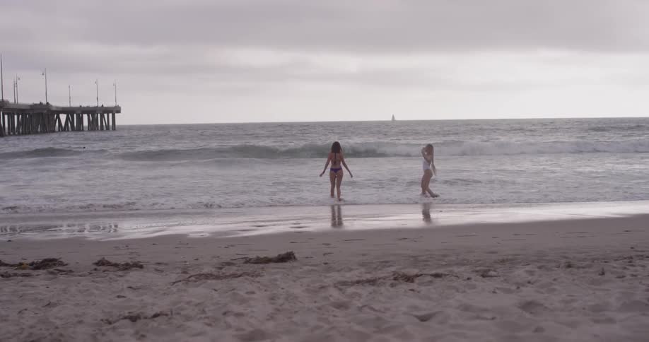 Two women in bikinis playing in the beach