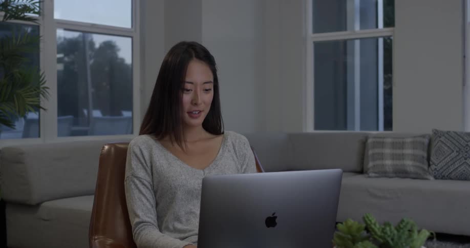 A woman smiling while working on her laptop at home