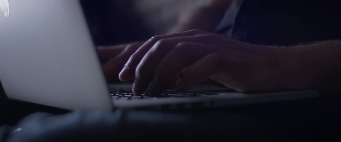 A person typing on their laptop while sitting on a couch