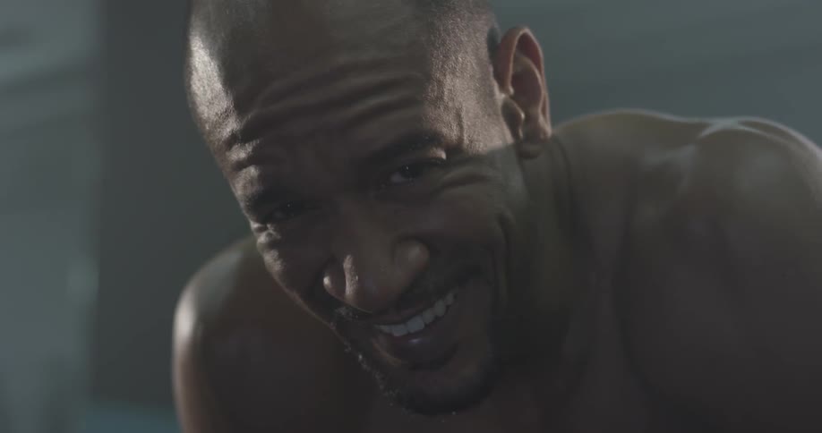 Shirtless man with hands on knees looking at camera and smiling