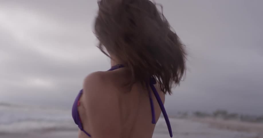 A woman dances in ankle deep ocean water