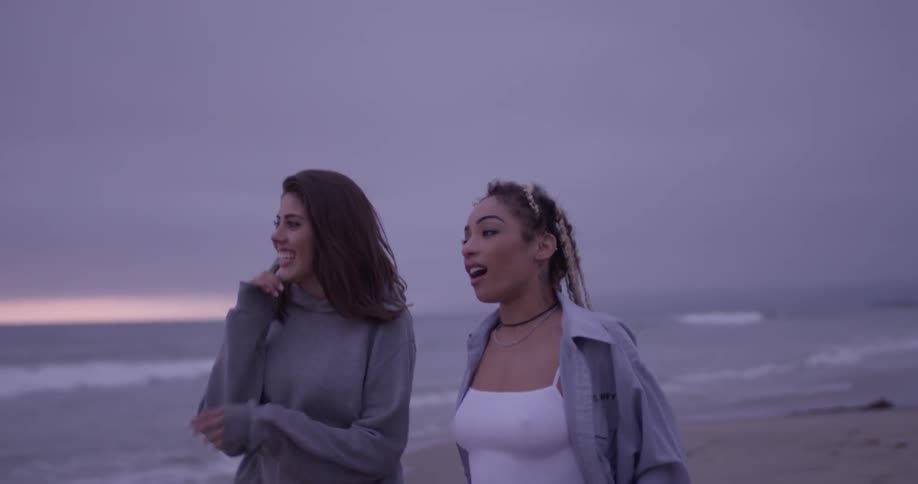 Two women walking on the beach on a cloudy day