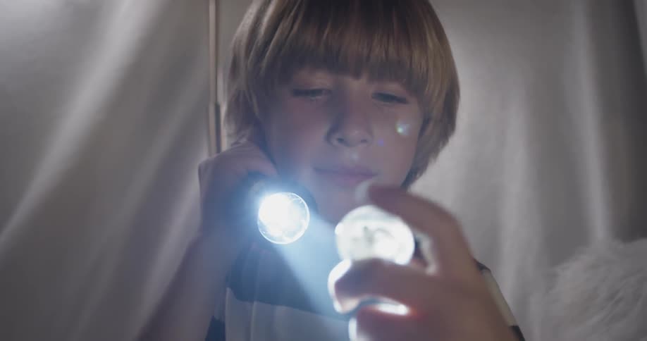 A boy is flashing a light in a tent