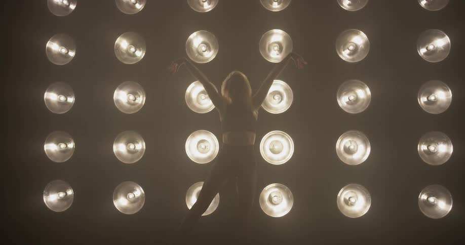 Woman dances in front of a large wall of lights