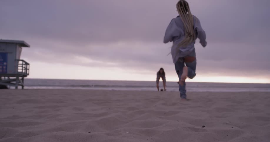 A woman kicking a football to another woman