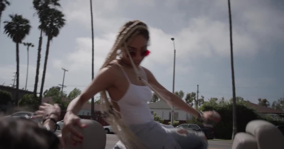 Two women jump in the back of a convertible and start dancing