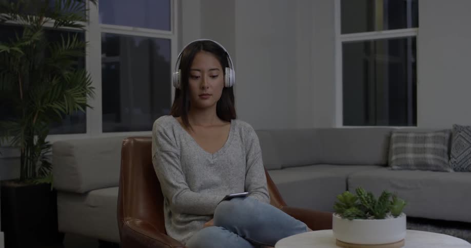 A woman puts on a large white pair of headphones and then dances