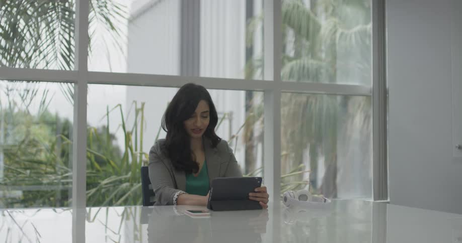 A woman that is typing on a tablet in an office