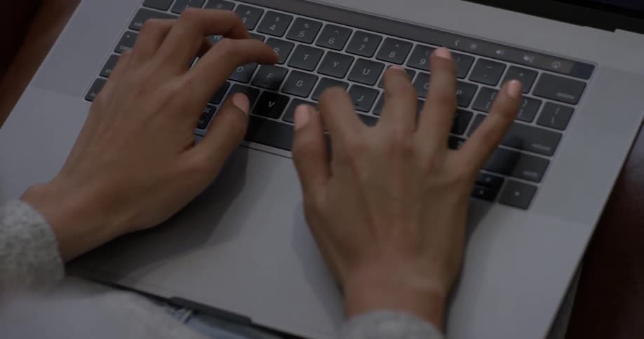 A woman is typing on a laptop