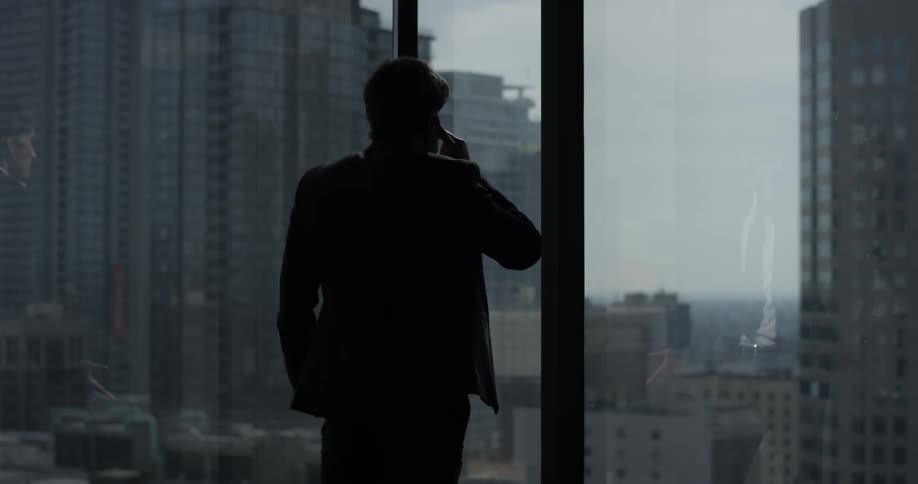 Man talking on phone near inside windows of building