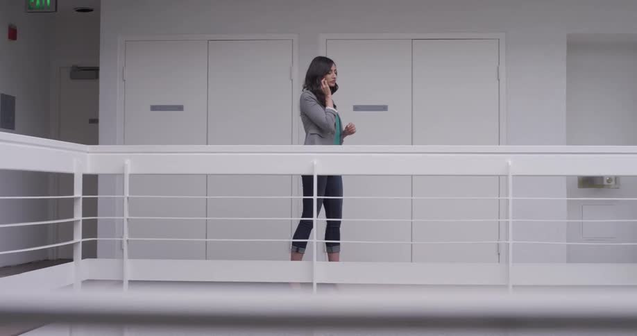 A woman by a railing speaking on the phone