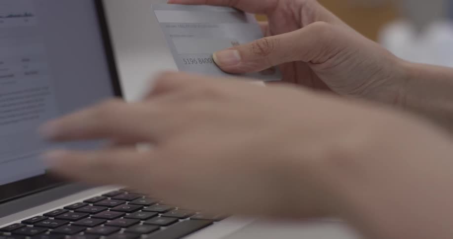 Person types their credit card number into a laptop