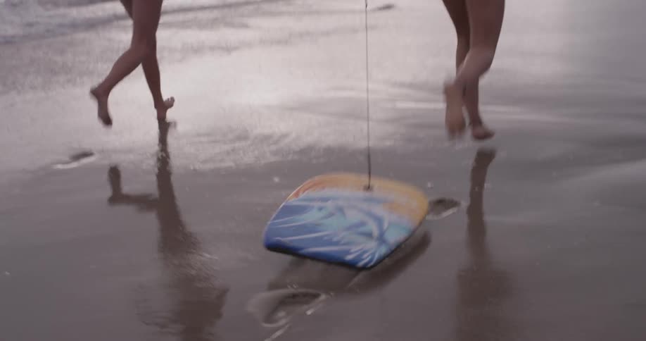 Two women dragging a boogie board down the ocean