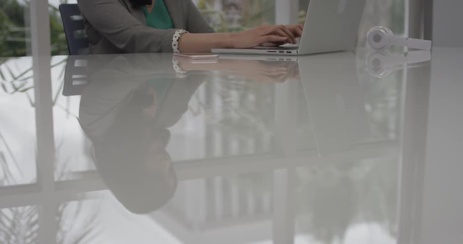 A woman typing on a laptop on a desk