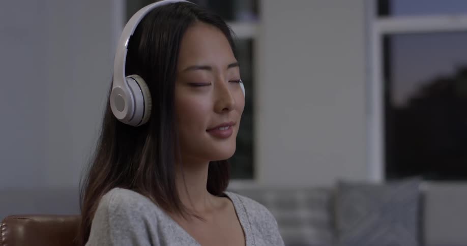 Woman smiles and nods her head as she listens to headphones